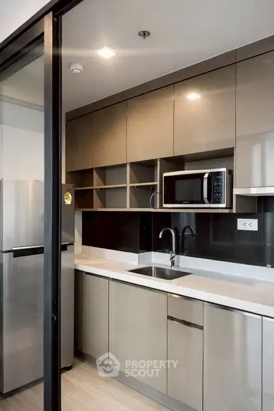 Modern kitchen with sleek cabinetry and built-in microwave in a contemporary apartment.