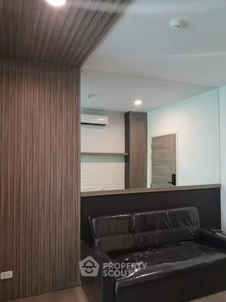 Modern living room with sleek wooden paneling and black leather sofa