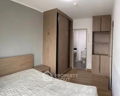 Spacious bedroom with ensuite bathroom and modern wooden furniture.