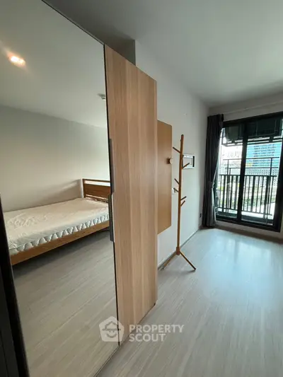Modern bedroom with wooden flooring and balcony view in a stylish apartment.