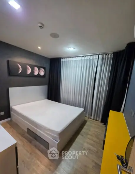 Modern bedroom with stylish decor and large window, featuring a comfortable bed and elegant wooden flooring.