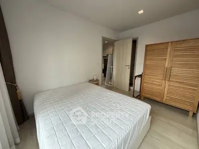 Modern bedroom with minimalist design featuring a cozy bed and wooden wardrobe.