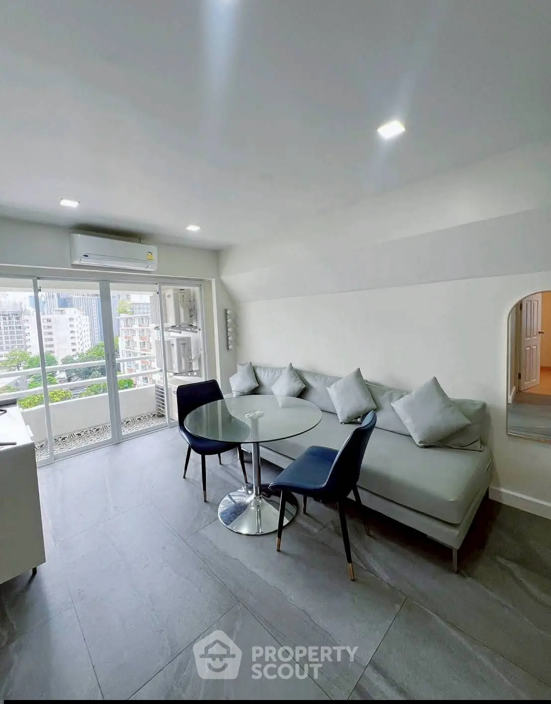 Modern living room with sleek furniture and city view from large windows.