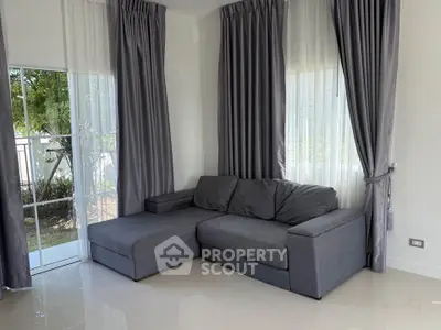 Modern living room with gray sectional sofa and large windows with curtains