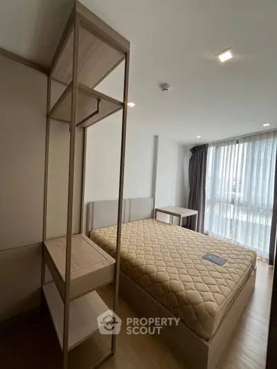 Modern bedroom with large window and stylish furniture in a cozy apartment.