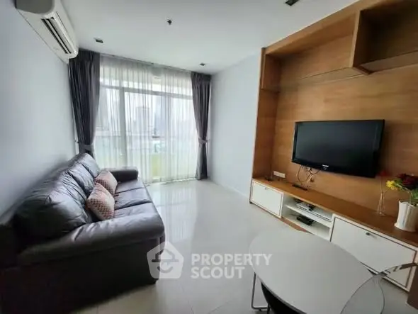 Modern living room with sleek furniture and large window offering natural light.