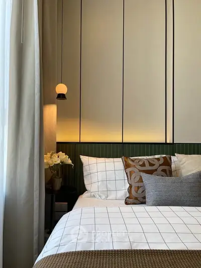 Elegant bedroom with modern decor and cozy lighting, featuring stylish pillows and a bedside lamp.