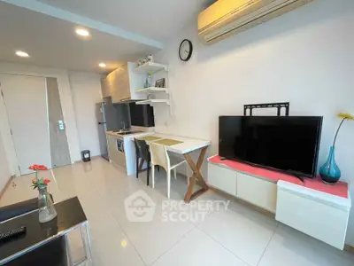 Modern living room with open kitchen, sleek furniture, and wall-mounted TV in a cozy apartment.