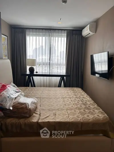 Cozy bedroom with modern decor, featuring a comfortable bed, wall-mounted TV, and a window with city views.