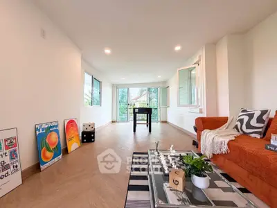 Spacious living room with modern decor and large windows offering natural light and garden view.