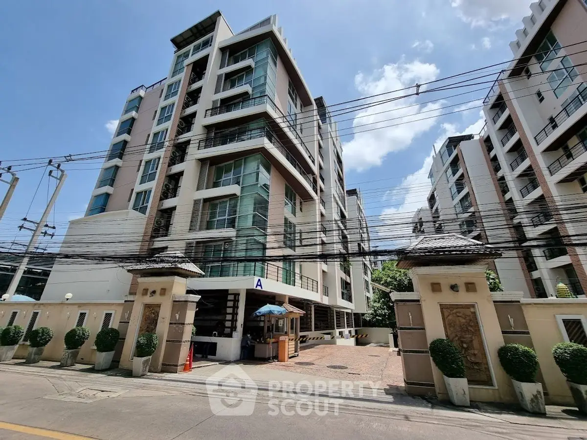 Modern condominium building exterior with clear blue sky and lush greenery.