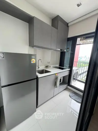 Modern compact kitchen with sleek cabinets and balcony view in urban apartment