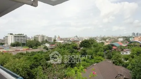 Stunning cityscape view from a high-rise balcony overlooking lush greenery and urban skyline.