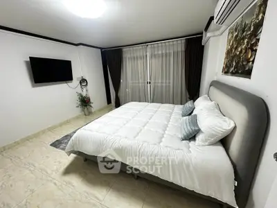 Spacious bedroom with modern decor and large window for natural light.