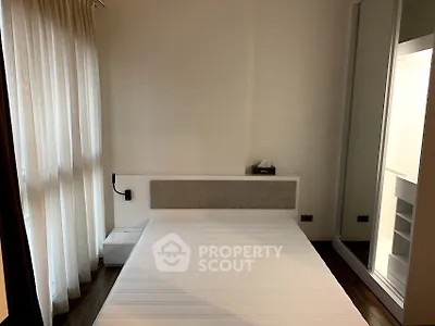 Cozy bedroom with large window and modern decor, perfect for relaxation.