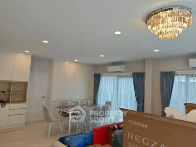 Spacious modern living room with elegant chandelier and dining area