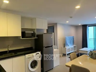 Modern apartment interior with kitchen and living area, featuring washing machine and fridge.