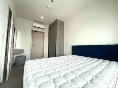 Modern bedroom with stylish decor and ample natural light, featuring a comfortable bed and sleek storage solutions.