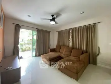Spacious living room with large brown sectional sofa and ceiling fan, featuring natural light from sliding glass doors.