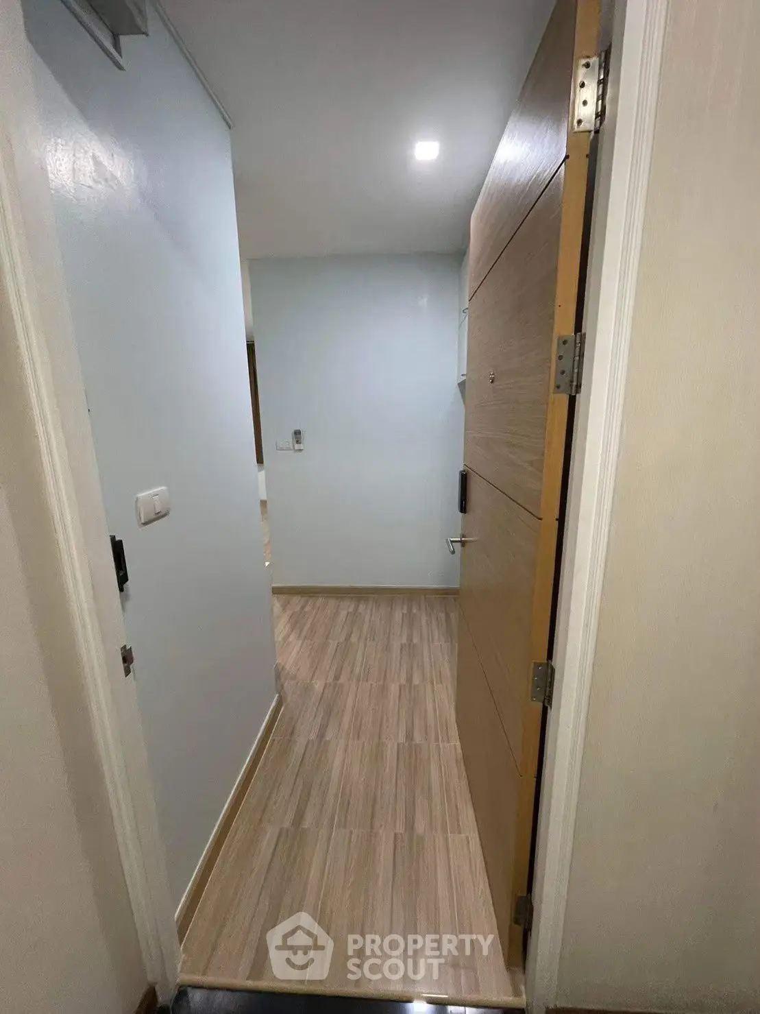 Modern apartment entrance with wooden door and sleek flooring