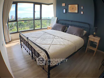 Spacious bedroom with large windows offering a stunning view, featuring a cozy bed and elegant decor.