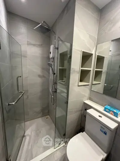 Modern bathroom with glass shower enclosure and sleek fixtures.