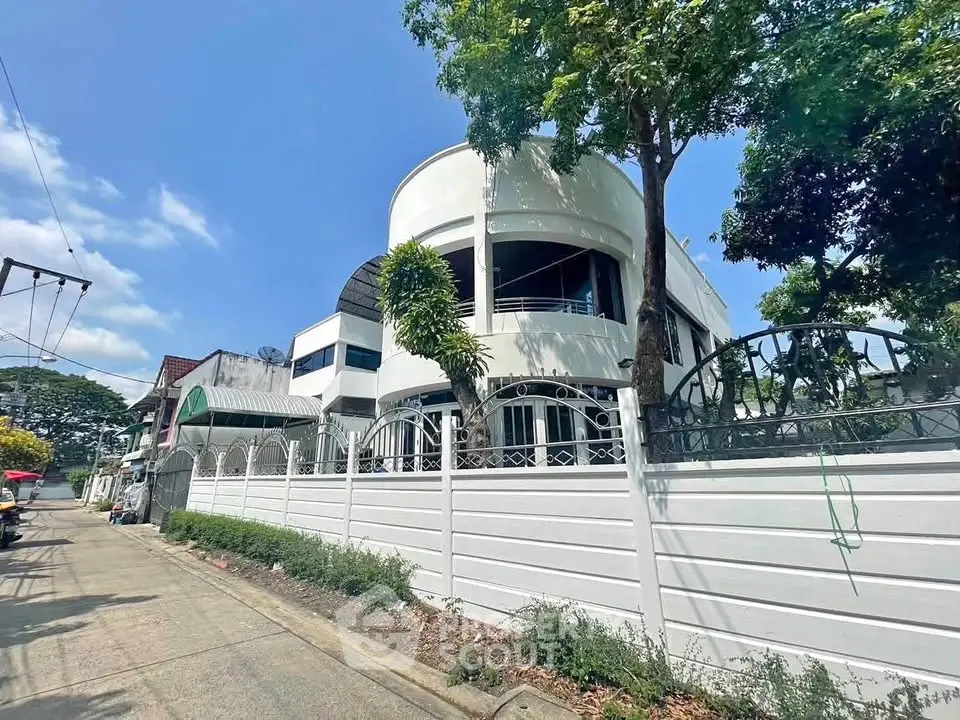 Stunning modern white building with unique architecture and lush greenery in a serene neighborhood.
