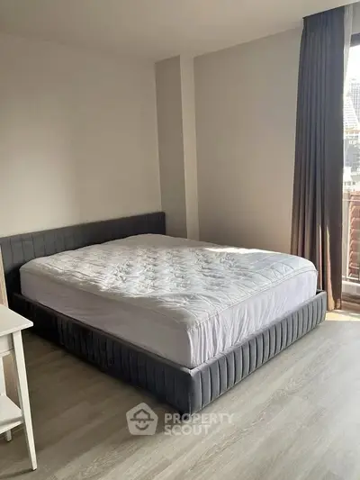 Spacious bedroom with modern bed and natural light in a stylish apartment.