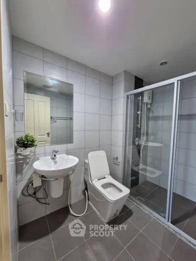 Modern bathroom with sleek fixtures and glass shower enclosure in a contemporary home.