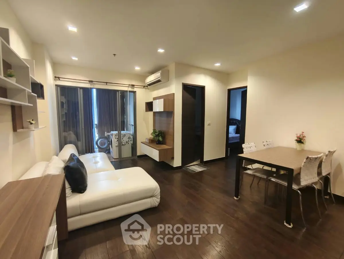 Modern living room with elegant decor and open dining area, featuring sleek furniture and warm lighting.