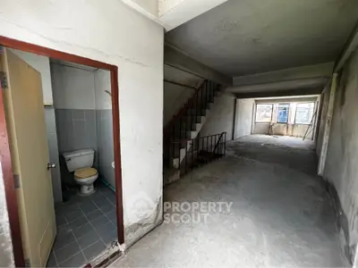 Spacious unfinished interior with staircase and small bathroom, ideal for renovation projects.