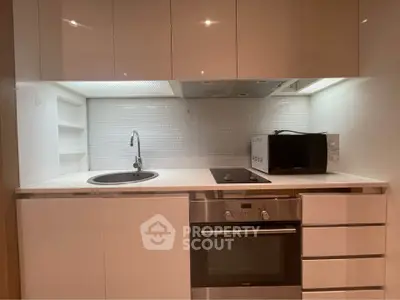 Modern compact kitchen with sleek white cabinets and built-in appliances