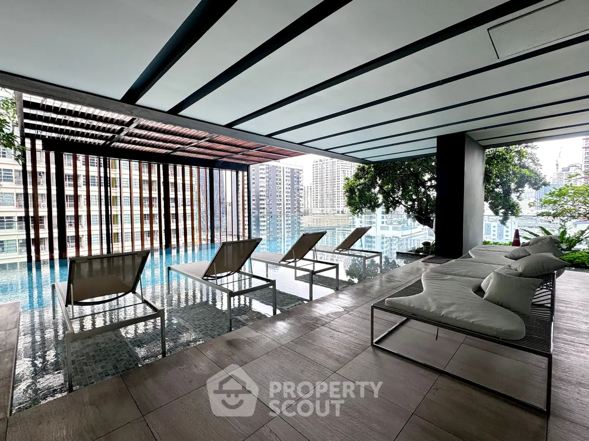 Luxurious rooftop pool area with modern lounge chairs and stunning city view, perfect for relaxation and leisure.
