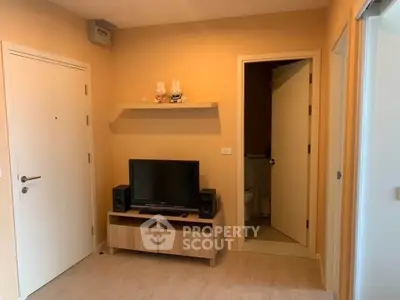 Cozy living room with TV stand and open bathroom door, perfect for compact living.