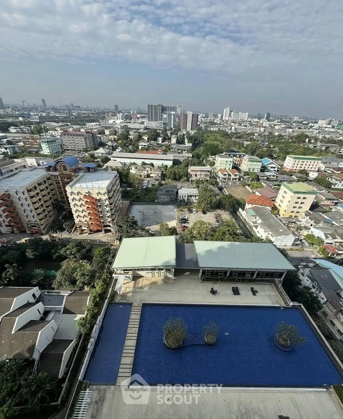 Stunning aerial view of cityscape with luxurious rooftop pool and lush surroundings.
