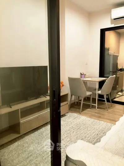 Modern living room with TV, dining area, and kitchen in open layout apartment.