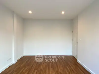 Spacious empty room with wooden flooring and white walls, ideal for customization.