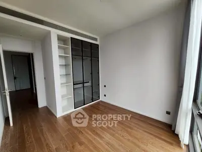 Spacious bedroom with wooden flooring and built-in closet in modern apartment