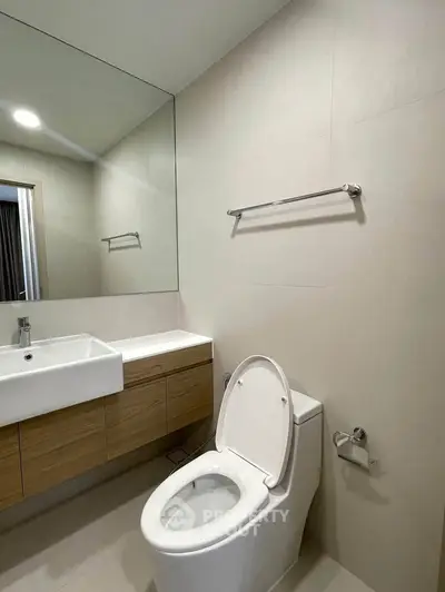 Modern bathroom with sleek fixtures and large mirror in a contemporary home.