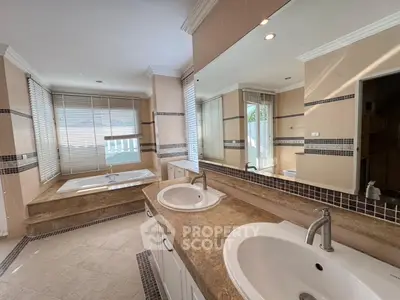 Luxurious bathroom with dual sinks and a spacious bathtub, featuring elegant tile work and ample natural light.