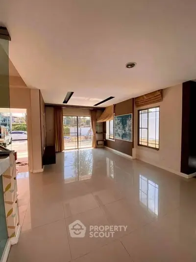 Spacious living room with large windows and glossy tiled floors