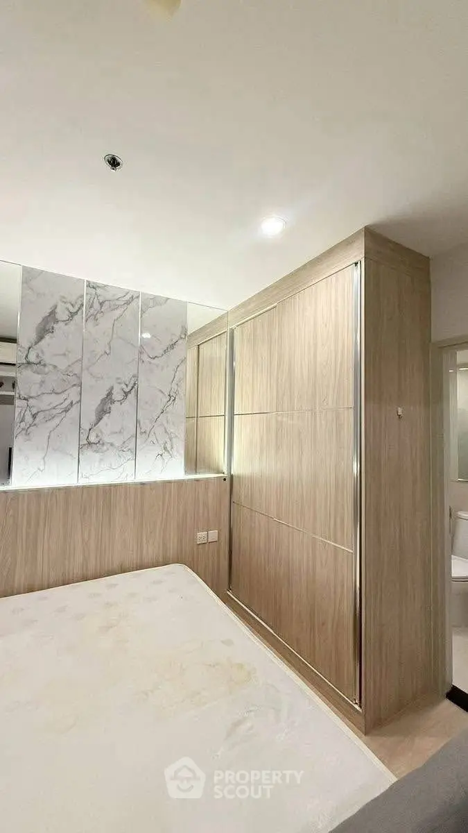 Modern bedroom with stylish wooden wardrobe and marble accent wall