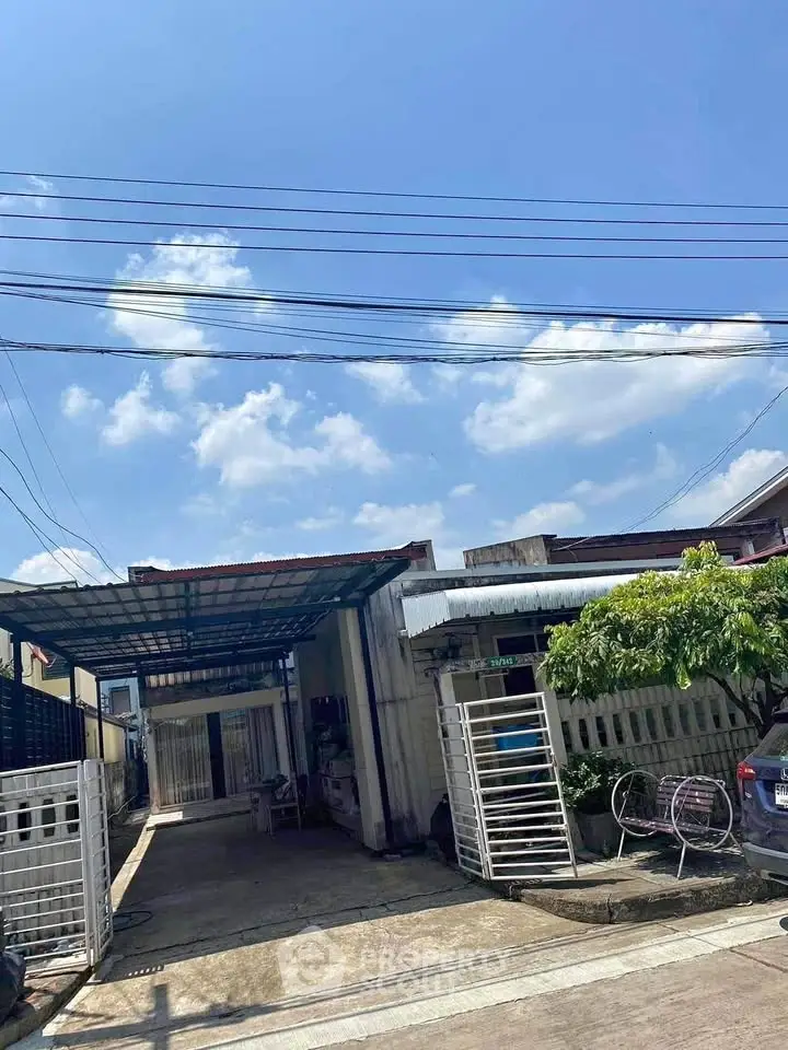 Charming single-story home with gated driveway and carport under a clear blue sky.