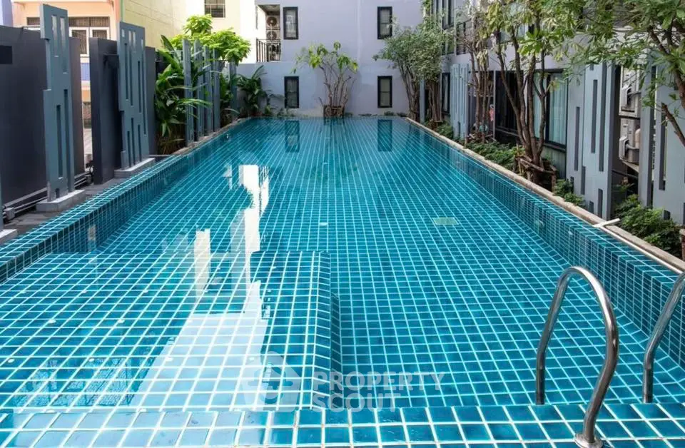 Luxurious residential pool with modern design and lush greenery, perfect for relaxation and leisure.