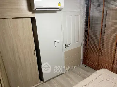 Cozy bedroom with modern air conditioning and wooden wardrobe, perfect for comfortable living.