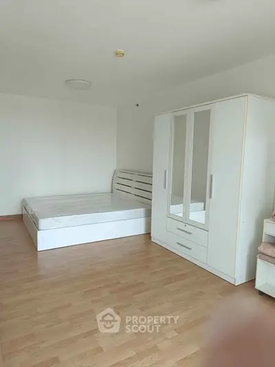 Spacious bedroom with modern white furniture and wooden flooring