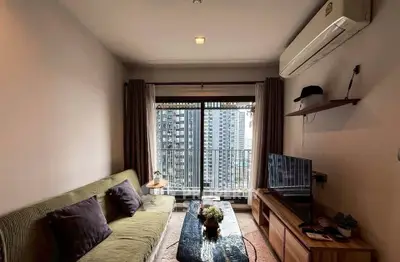 Modern living room with city view, featuring sleek furniture and large window for natural light.