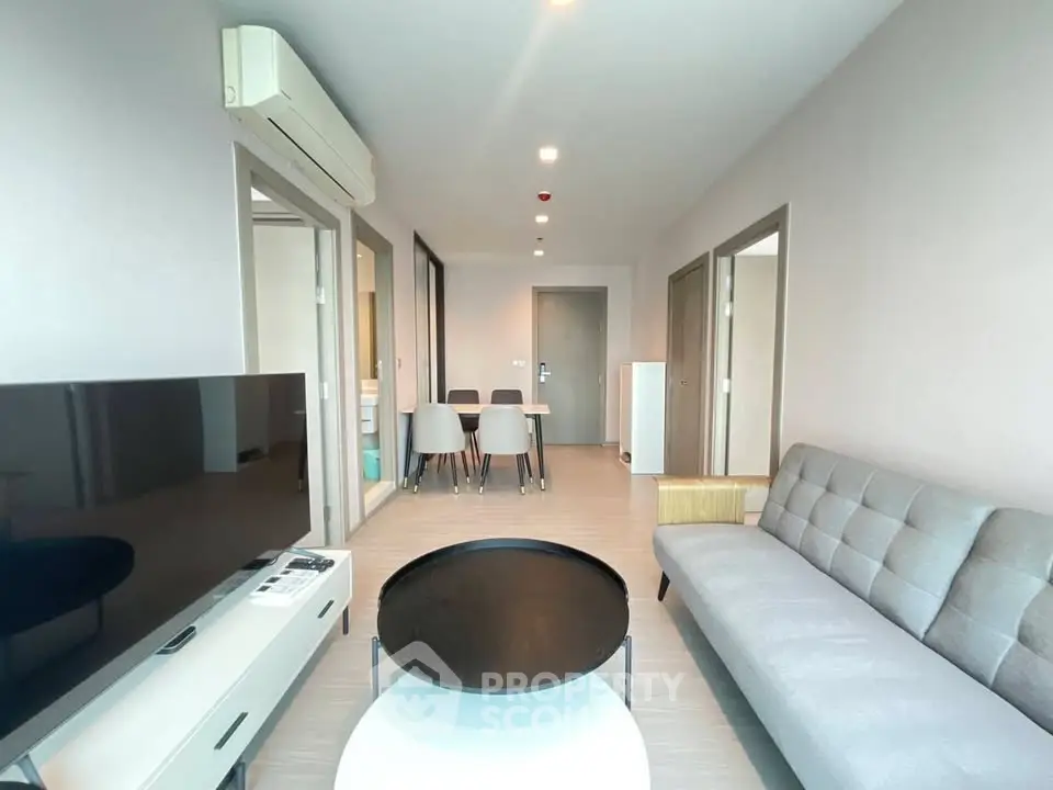 Modern living room with sleek furniture and open layout, featuring a stylish sofa and dining area.