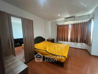 Spacious bedroom with wooden flooring and large window for natural light.