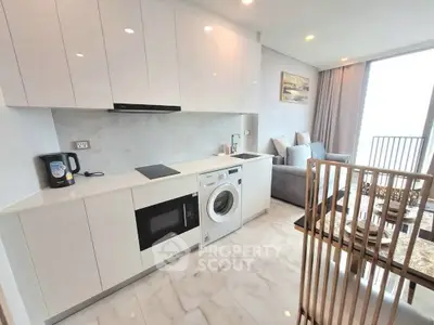 Modern open kitchen with sleek appliances and cozy living area in a bright apartment.